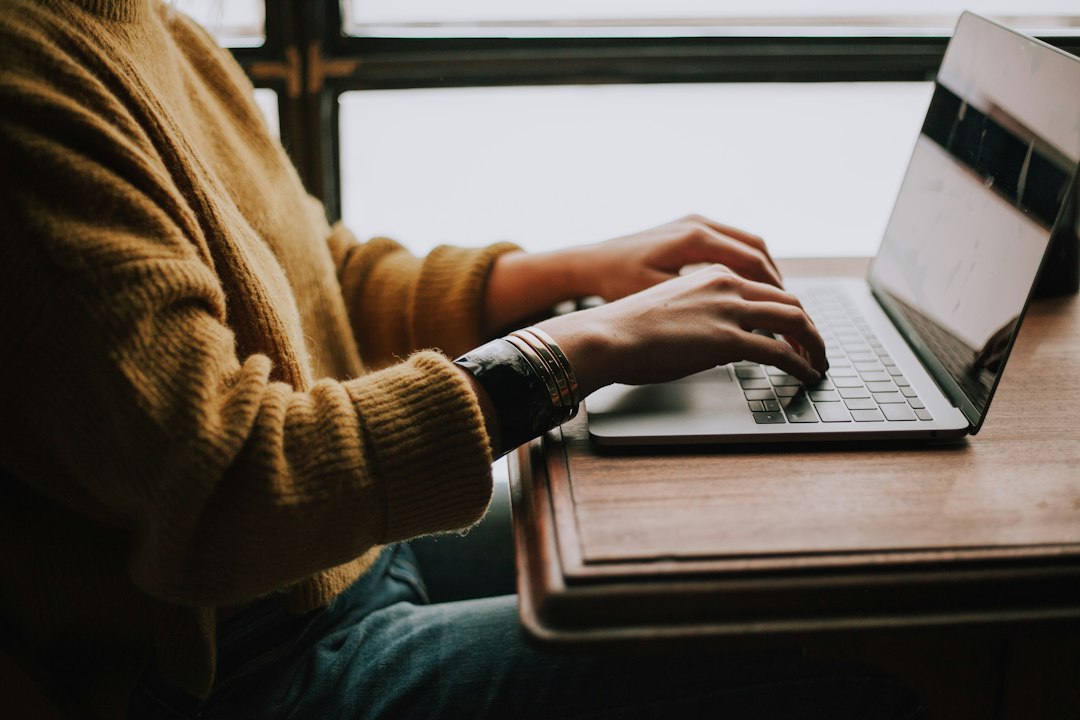 Hands typing on a laptop, editing the name on a Microsoft account so Windows 10 shows it at sign-in