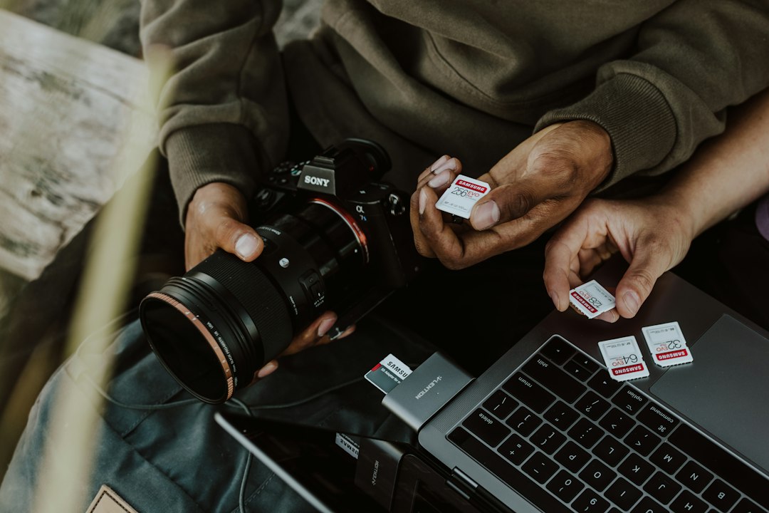 Photographer holding a camera whose memory card is about to be formatted on a PC
