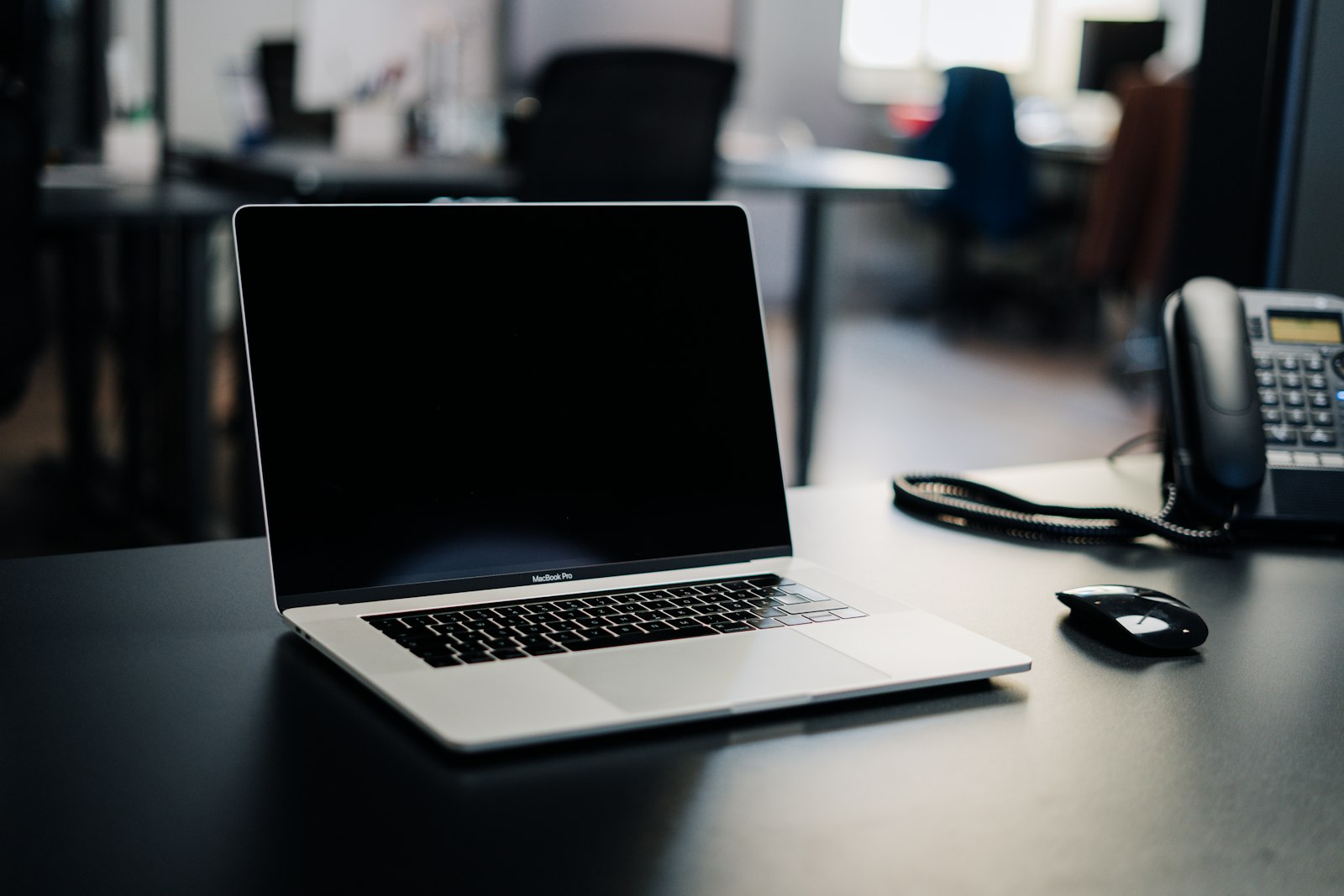 Laptop with a black screen on a dark desk