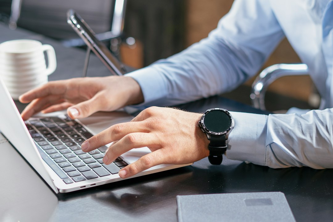 Person typing on a laptop at a desk, representing Microsoft Word tips and tricks for writing faster