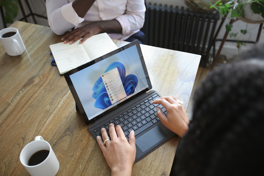 Two people working on a Windows laptop, where Task Manager can end stuck Microsoft Edge processes