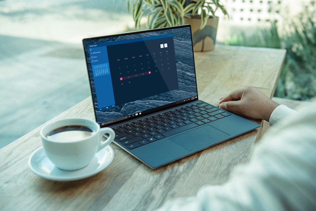 Person using a black laptop on a wooden table to reinstall the Microsoft Store