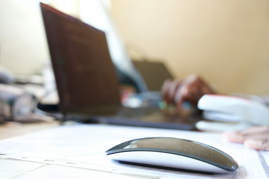 Computer mouse on a desk next to a laptop whose cursor has disappeared