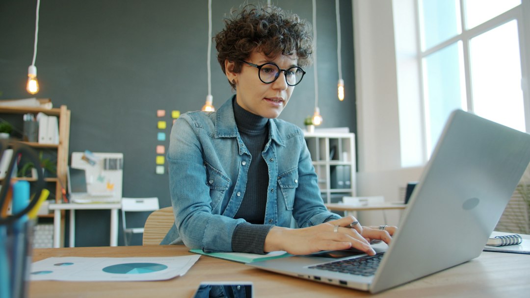 Woman working on a laptop at an office desk, the kind of setup where classic Outlook is used for work email