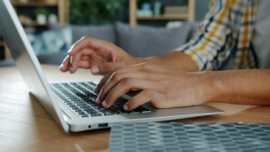 Hands typing on a laptop at home while switching Outlook back to the classic version