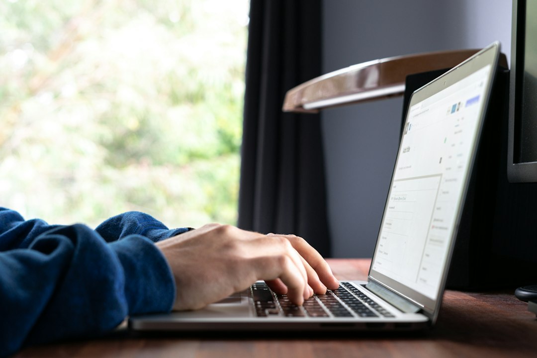 Hands typing on a laptop keyboard, entering a runas command to start a program as another user